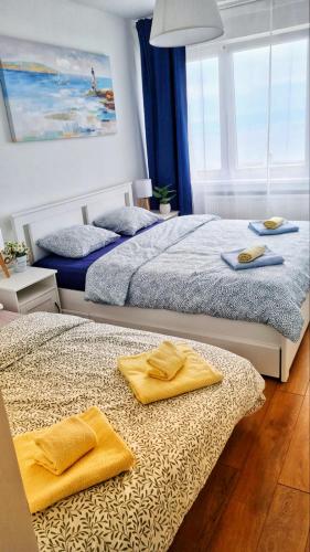 two beds in a bedroom with yellow towels on them at Sunflower Sky Apartment in Rijeka