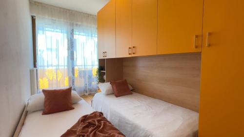 two beds in a room with yellow cabinets at Mazzarona Family Apartment - Luminoso appartamento con piscina al secondo piano in Sirmione