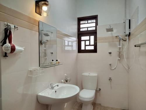 a white bathroom with a toilet and a sink at Cosy White Palace in Negombo