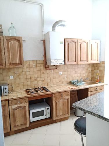 une cuisine avec des armoires en bois et un four à micro-ondes dans l'établissement Apartement Coeur Nice Ville ! Zone Touristique !, à Nice