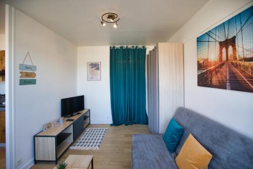 un salon avec un canapé bleu et une télévision dans l'établissement Le sommet citadin avec vue, à Annecy