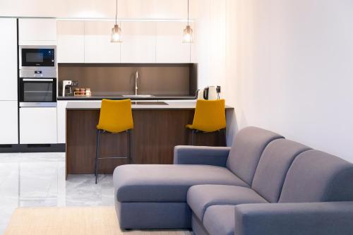 a living room with a couch and two yellow chairs at Florette Suite 1BR with Stunning Lounge Terrace by ArcoBnb in Il-Furjana
