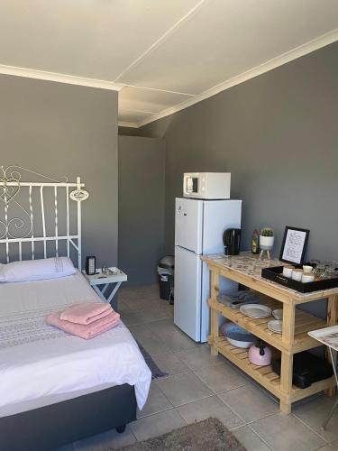 a bedroom with a bed and a refrigerator and a table at Arendsnest in Springbok