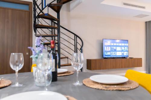 a table with plates and wine glasses and a television at Florette Suite 1BR with Stunning Lounge Terrace by ArcoBnb in Il-Furjana