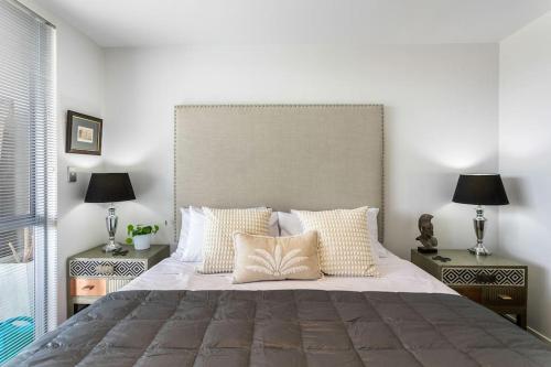 a bedroom with a large bed with two night stands at Perfection, Style, 2BR, 2BA, 2 Free Carpark 400m to Eden Park in Auckland