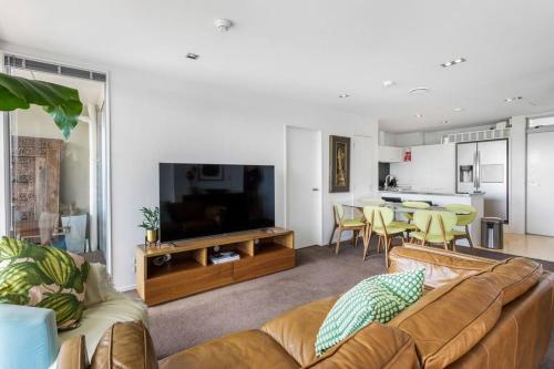 a living room with a couch and a tv and a table at Perfection, Style, 2BR, 2BA, 2 Free Carpark 400m to Eden Park in Auckland