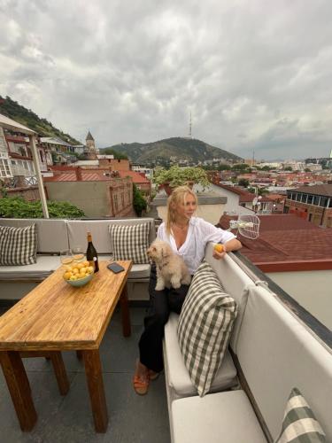 a woman sitting on a balcony with a dog at Betlemi Old Town Hotel in Tbilisi City