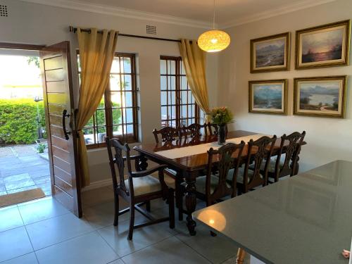 a dining room with a wooden table and chairs at Paarl Crystal Family Home in Paarl