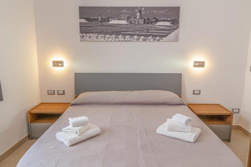 a bedroom with a large bed with two white towels at Isgrò Rooms in Marsala