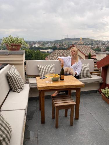 a woman sitting on a balcony with a table at Betlemi Old Town Hotel in Tbilisi City