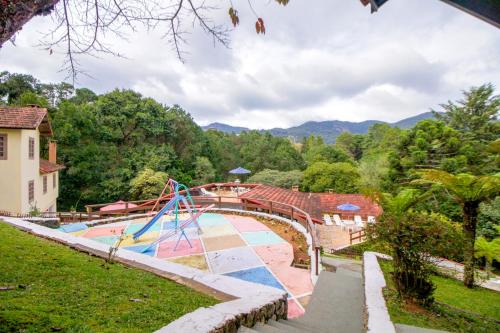 a swimming pool with a slide and a playground at VELINN Hotel Ninho do Falcão in Monte Verde