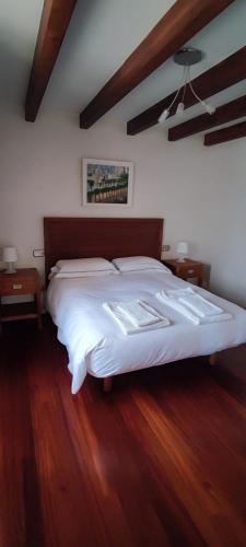 a bedroom with a large white bed and wooden floors at Casa Ria do Anllons in Ponteceso
