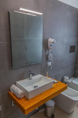 a bathroom with a sink and a mirror and a toilet at Isgrò Rooms in Marsala