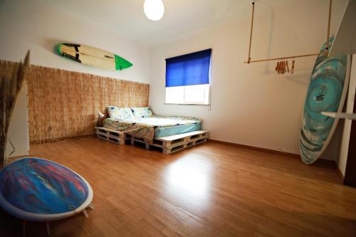 a room with a bed and a surfboard on the wall at Surf House in Aljezur