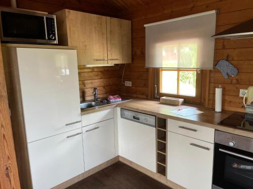 a kitchen with white cabinets and a microwave at Blockhaus FerienZauber II in Bromskirchen