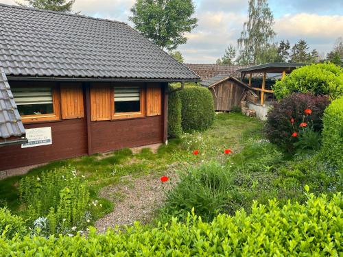 a garden with red flowers and a house at Blockhaus FerienZauber III in Bromskirchen