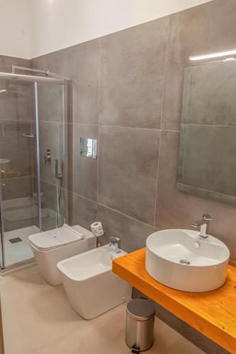 a bathroom with a sink and a toilet and a shower at Isgrò Rooms in Marsala