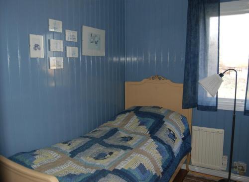 1 dormitorio con 1 cama con pared azul en Bjurmangården Recycled Glass Design en Sjöbo