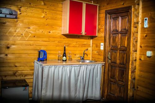 a kitchen with a sink and red cabinets and a table at Wooden Village Resort in Ponari