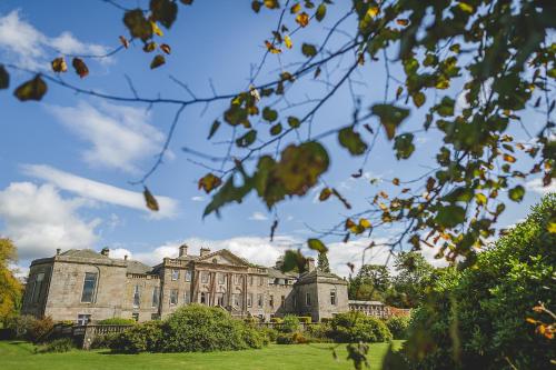 a large stone building with trees in front of it at Springkell in Eaglesfield