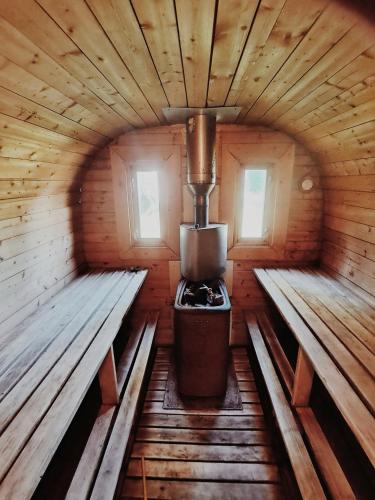 a stove in a wooden cabin with two benches at Koka namiņš "Pasaka" in Vecumnieki