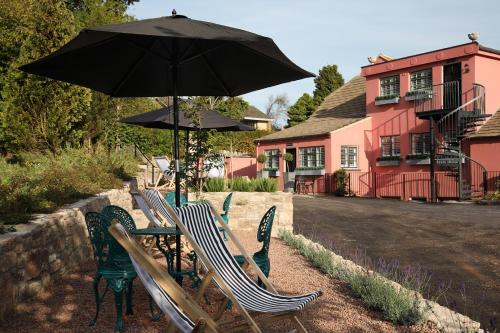 a table and chairs with an umbrella in front of a building at Cathedral View - Romantic Wye Valley Country House 1 Bed Apartment - Dog Friendly in Coleford