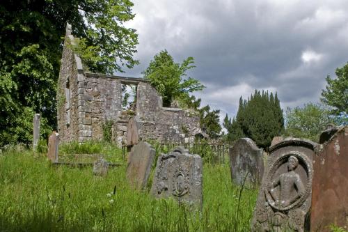 an old stone cemetery in front of a building at Springkell in Eaglesfield
