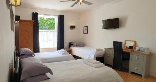 a room with three beds and a television in it at Midway Guest House in Torquay
