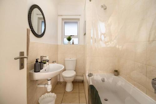 a bathroom with a sink and a toilet and a tub at Funky 2bed apartment with multipurpose room! in Cape Town