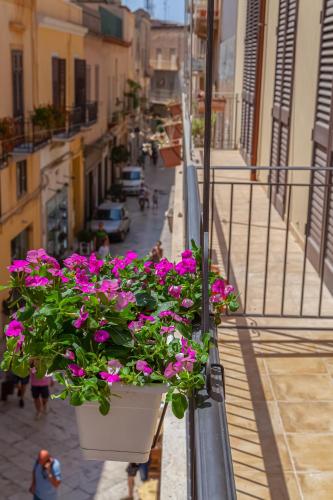 a balcony with a bunch of pink flowers in buckets at Isgrò Rooms in Marsala
