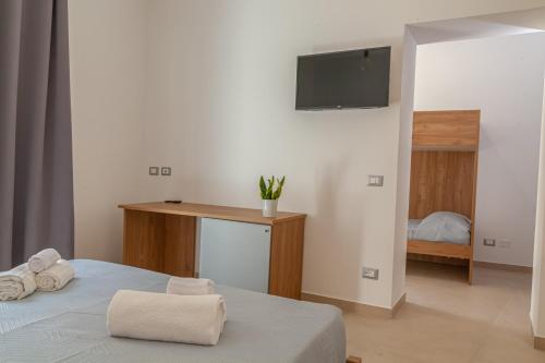 a bedroom with a bed with a tv on the wall at Isgrò Rooms in Marsala