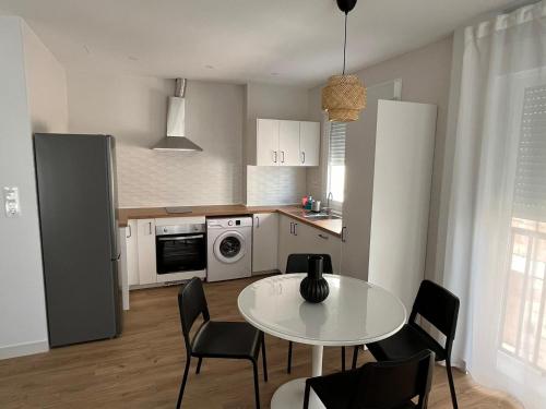 a kitchen with a white table and chairs and a table and a kitchen at Apartamento San Antonio 1 in Carboneras