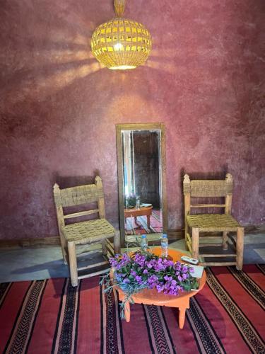a room with two chairs and a table with flowers on it at La Ferme Berbere Adult only in El Harkat