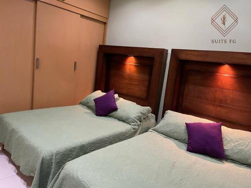 two beds in a room with purple pillows at Suite FG in San Juan de los Lagos