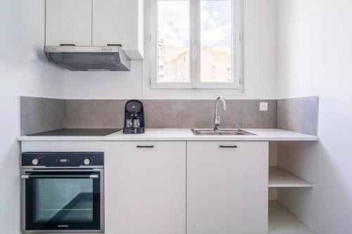 une cuisine blanche avec un évier et une cuisinière dans l'établissement Studio Cosy Proche Paris - Montreuil, à Montreuil
