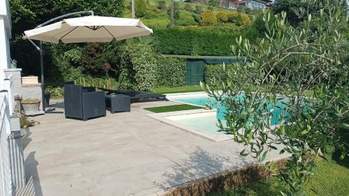 a patio with an umbrella and a swimming pool at Margot Ca Bianca Dormelletto Lago Maggiore in Dormelletto