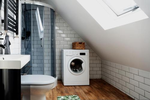 a bathroom with a washer and dryer and a sink at Chatka Rybaka - wygodny dom z podwórkiem in Łeba
