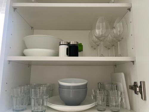 - une étagère de cuisine avec des bols et des verres dans l'établissement Modern Renovated Apartment -15 min Orly airport, à Viry-Châtillon