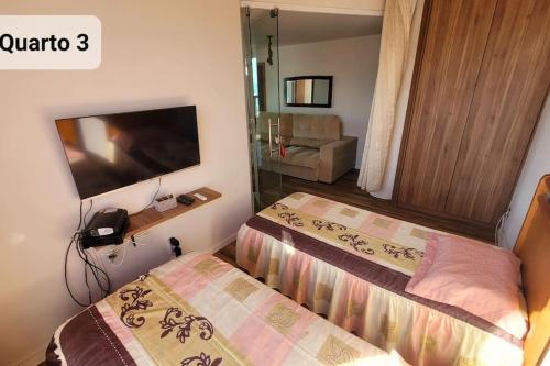 une chambre avec un lit et une télévision à écran plat dans l'établissement Lindo apto de frente para o mar, à Serra