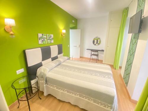 a bedroom with a large bed with green walls at Hostal Fabiola in Seville