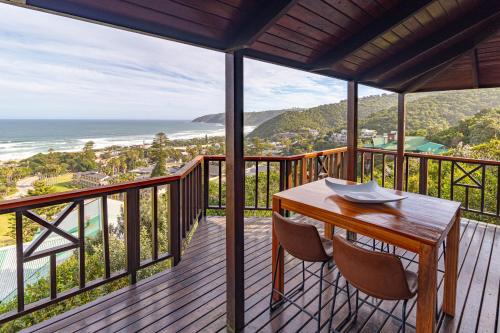a balcony with a table and chairs and the ocean at Peak's Cabin - Endless Ocean Views - Fireplace - Fast WiFi in Wilderness