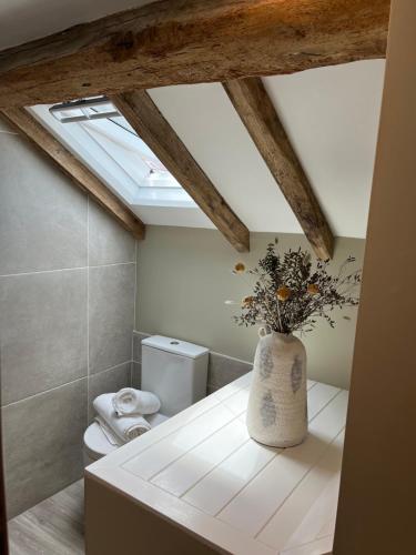 a bathroom with a toilet and a vase with flowers at Posh Little Cottage in Llangollen