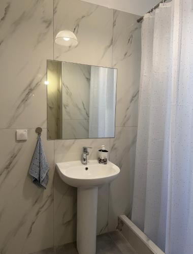 a white bathroom with a sink and a mirror at Petaluda House 5 in Athens