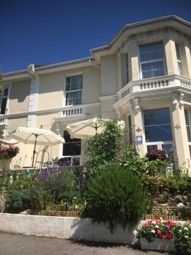 a house with umbrellas and flowers in front of it at Fleurie Guest House in Torquay