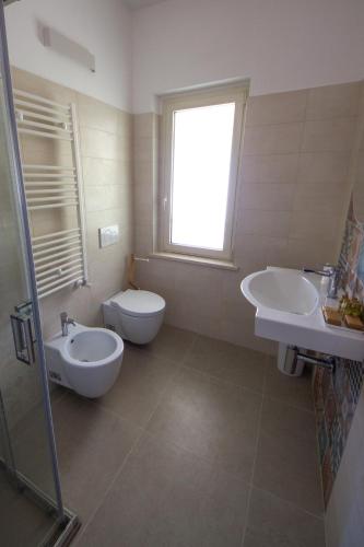a bathroom with two sinks and a toilet and a window at Villa la sorgente in Guardia Vomano