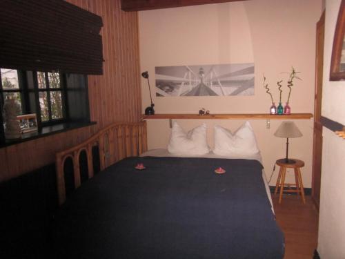 a bedroom with a bed with a blue blanket and pillows at Apartment Holmsland in Hvide Sande