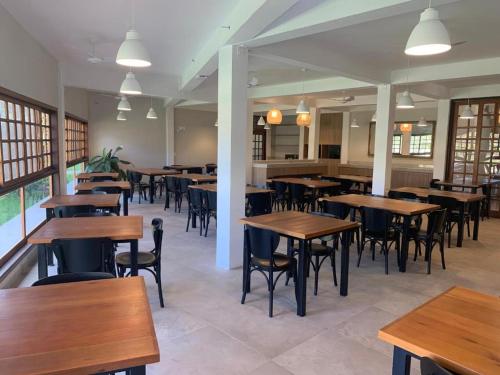 an empty restaurant with wooden tables and chairs at Delta Maresias Club by Smart Sharing in Maresias
