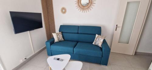 un canapé bleu dans un salon avec une télévision dans l'établissement Résidence Vera Cruz à 50m de la plage, à Canet