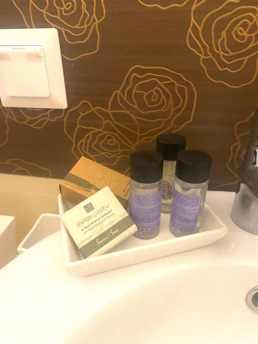 a bathroom sink with three bottles of cosmetics on a shelf at Gardenista in Gerakas near to airport in Athens