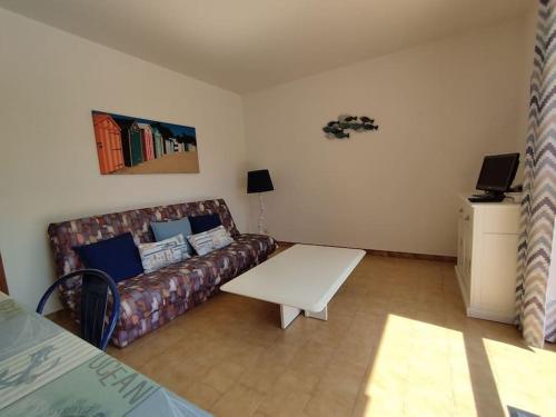 un salon avec un canapé et une table dans l'établissement Maisonnette à Chaucre en résidence avec piscine collective, à Saint-Georges-dʼOléron